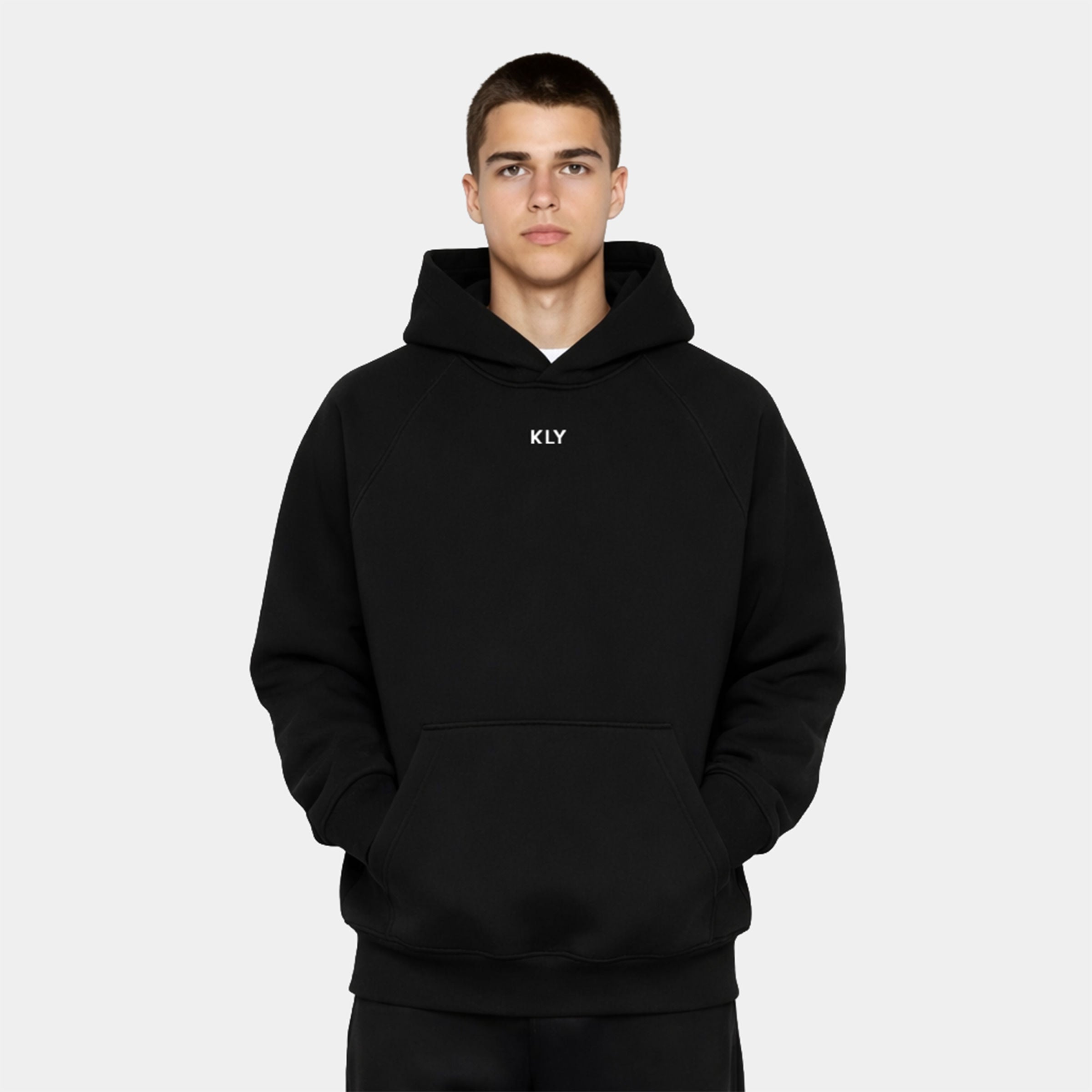 Male model facing forward in the KLY Original Hoodie in Black, hands in the kangaroo pocket